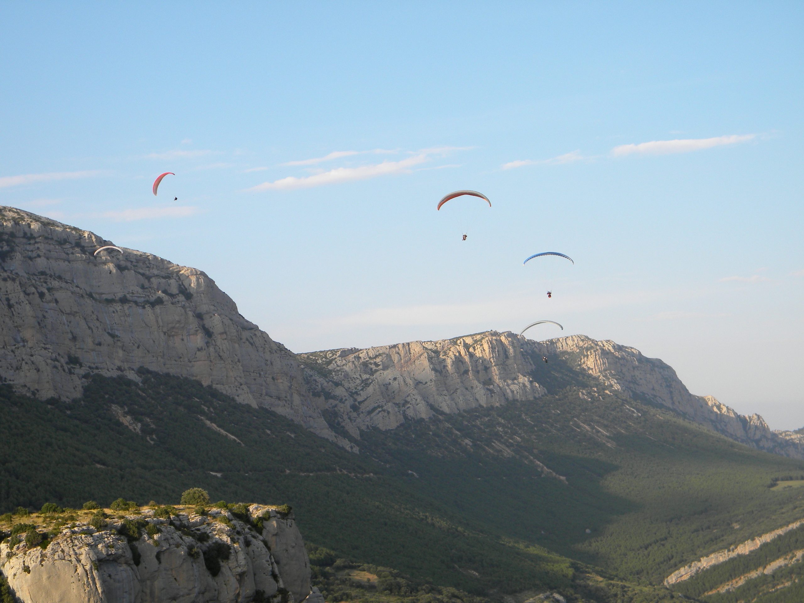Parapentes en vol devant une falaise calcaire au coucher du soleil