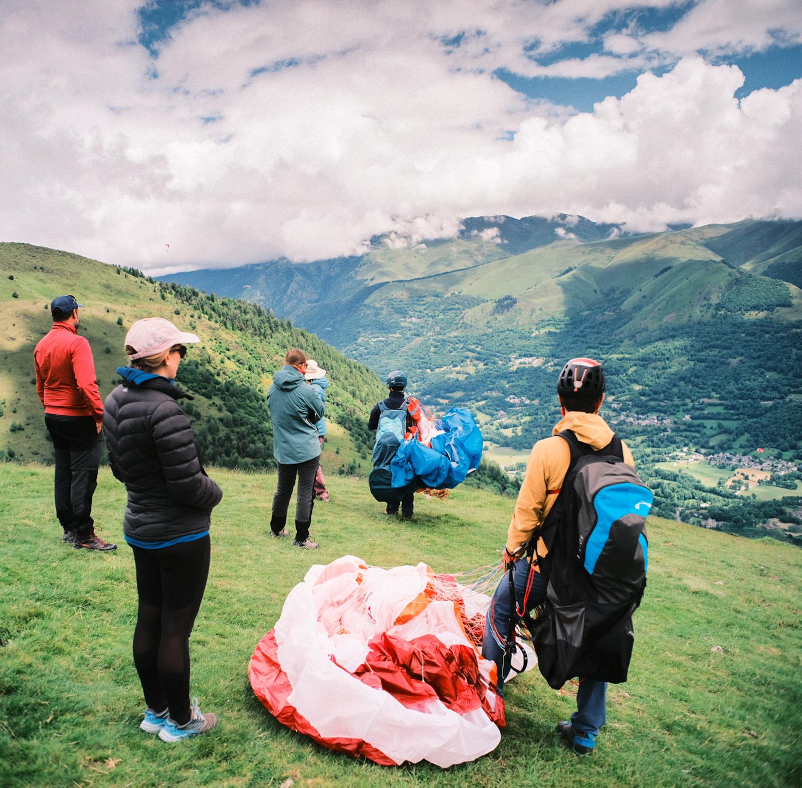 Groupe de pilotes préparant leurs ailes sur le déco face à la vallée